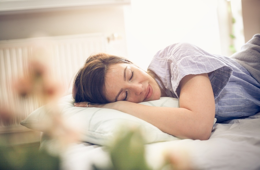 Young woman sleeping in bed for dental implant aftercare